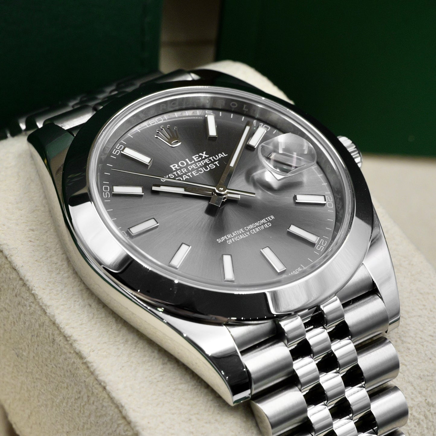 Silver Rolex watch with a dark face on a beige surface