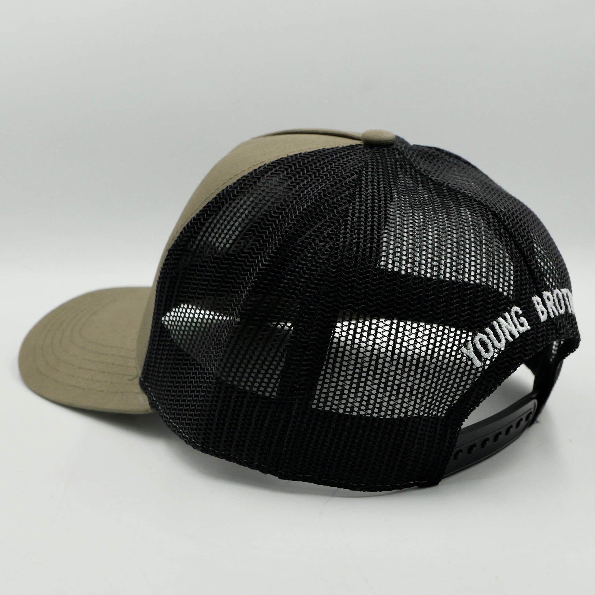 Black mesh cap with beige bill on a light gray background