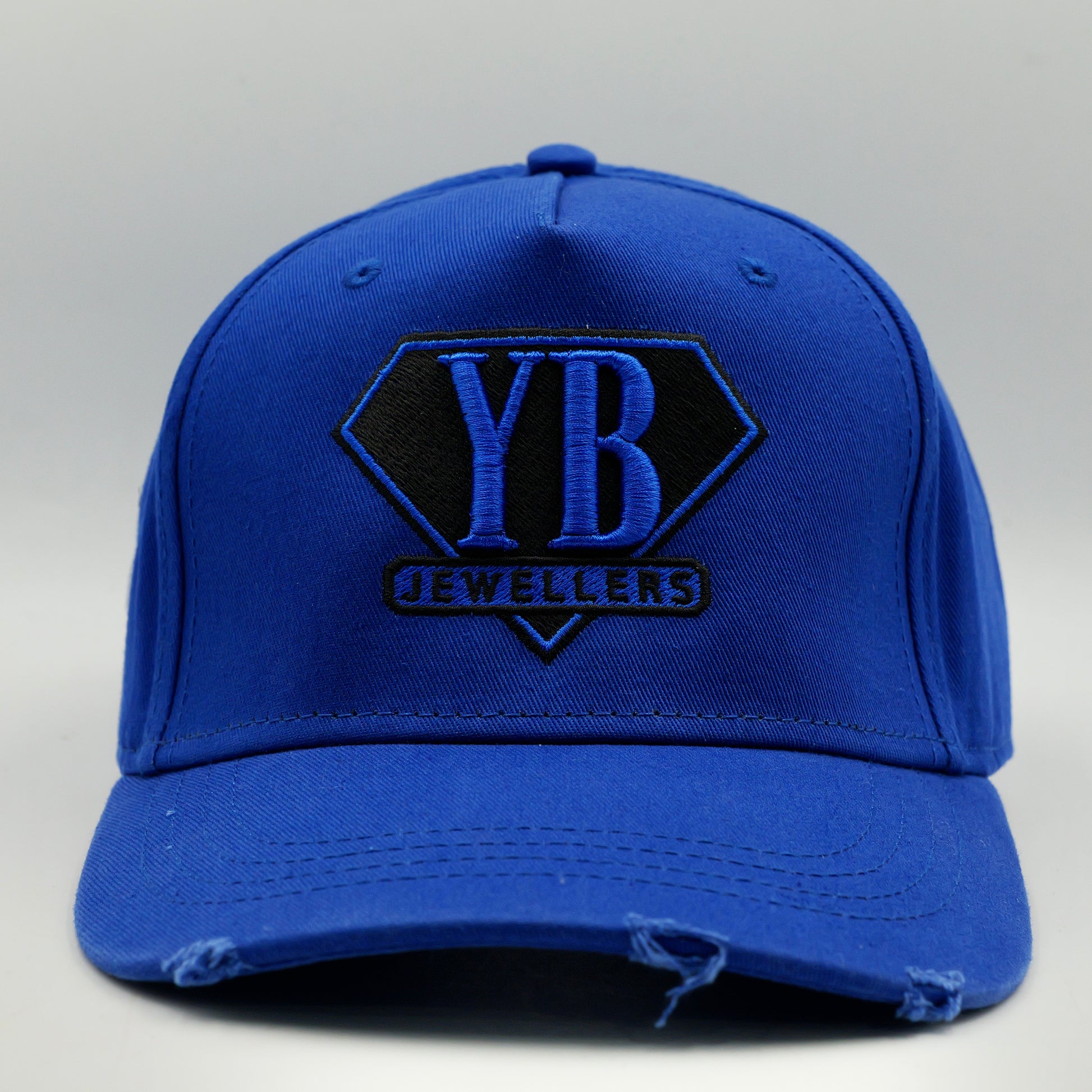 Blue cap with YB Jewellers logo on a gray background