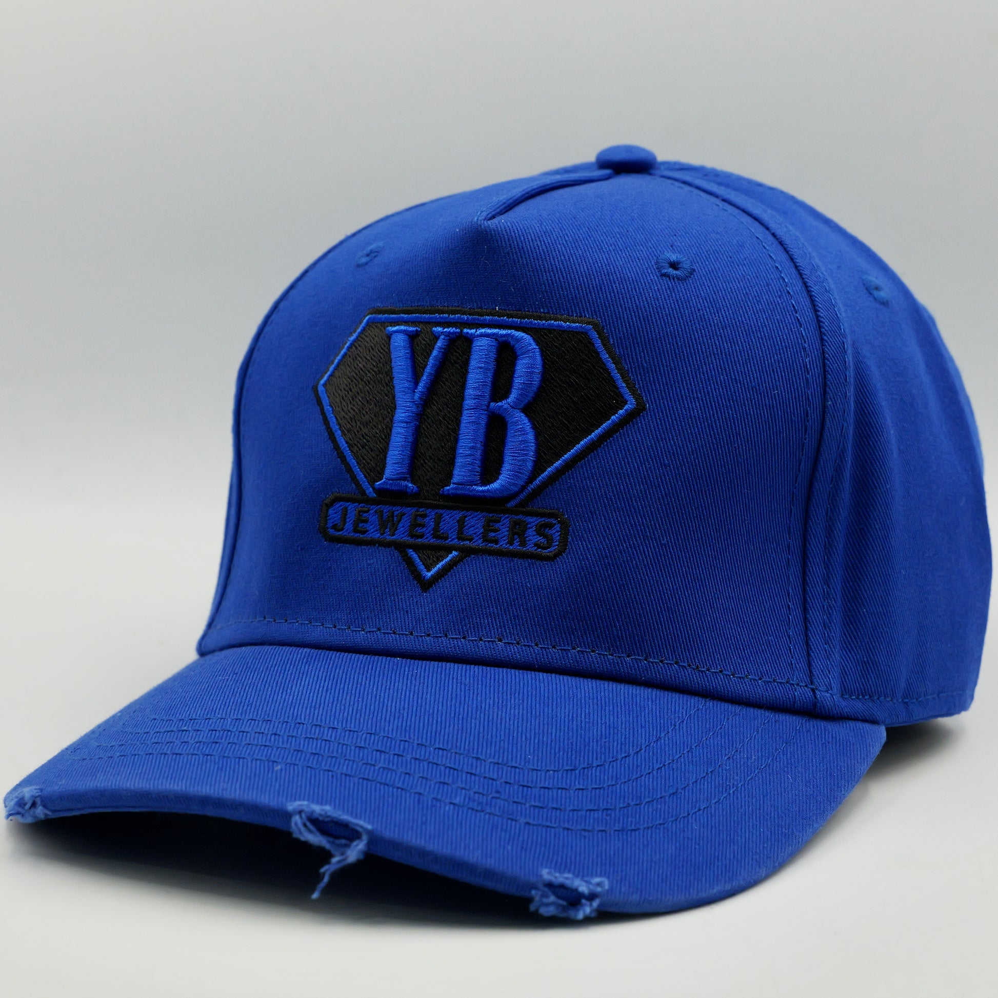 Blue cap with 'YB Jewelers' logo on a gray background