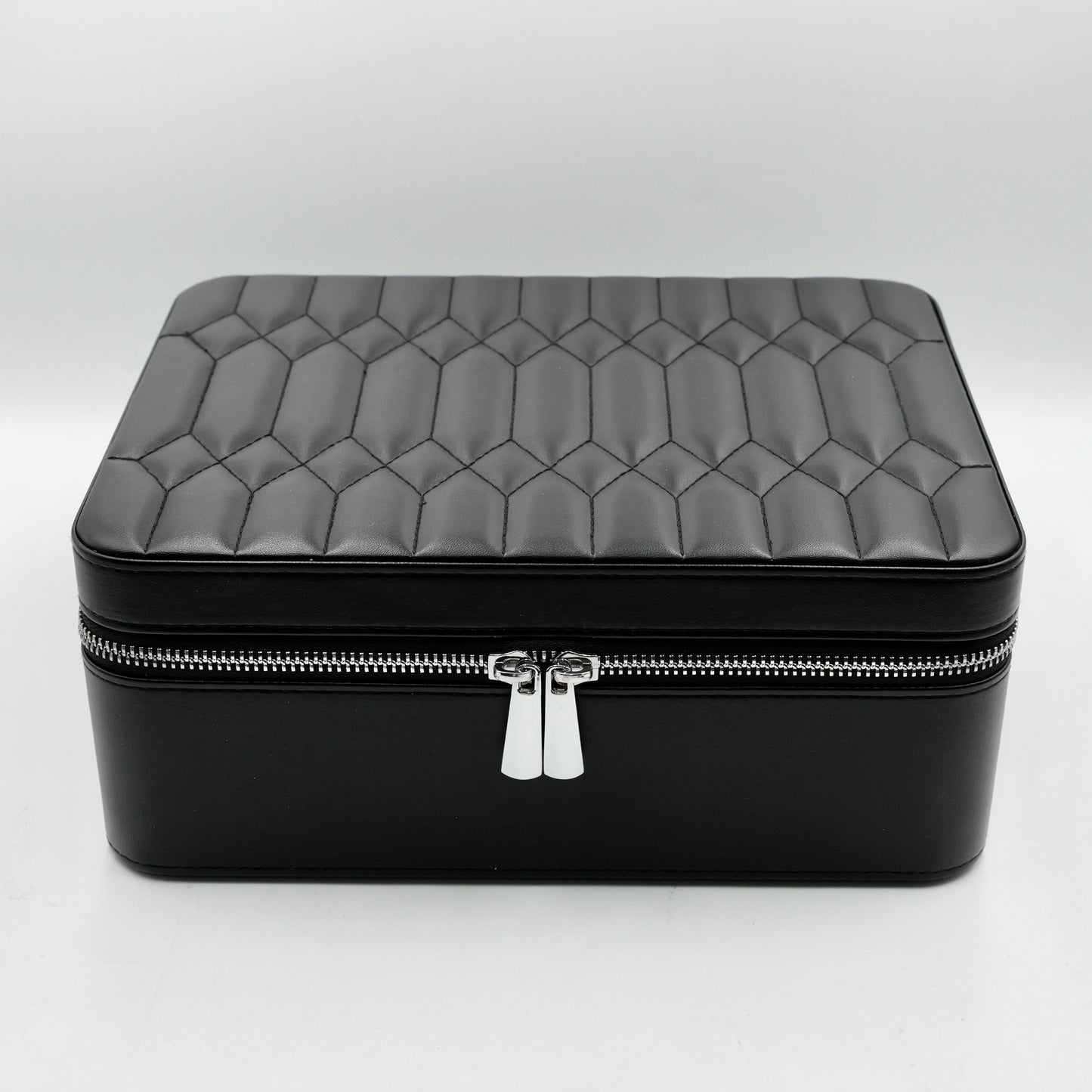 Black quilted jewelry box with a silver zipper on a white background