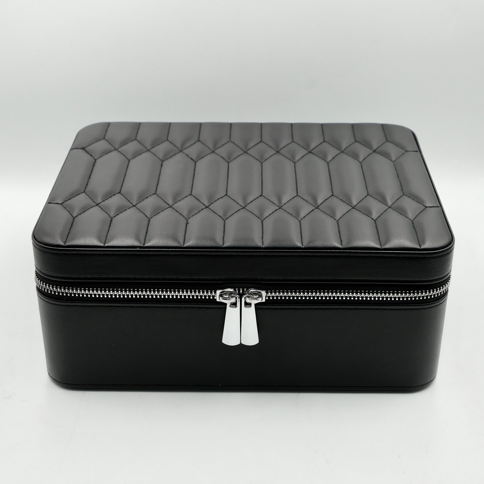 Black quilted jewelry box with a silver zipper on a white background