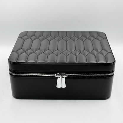 Black quilted jewelry box with a silver zipper on a white background